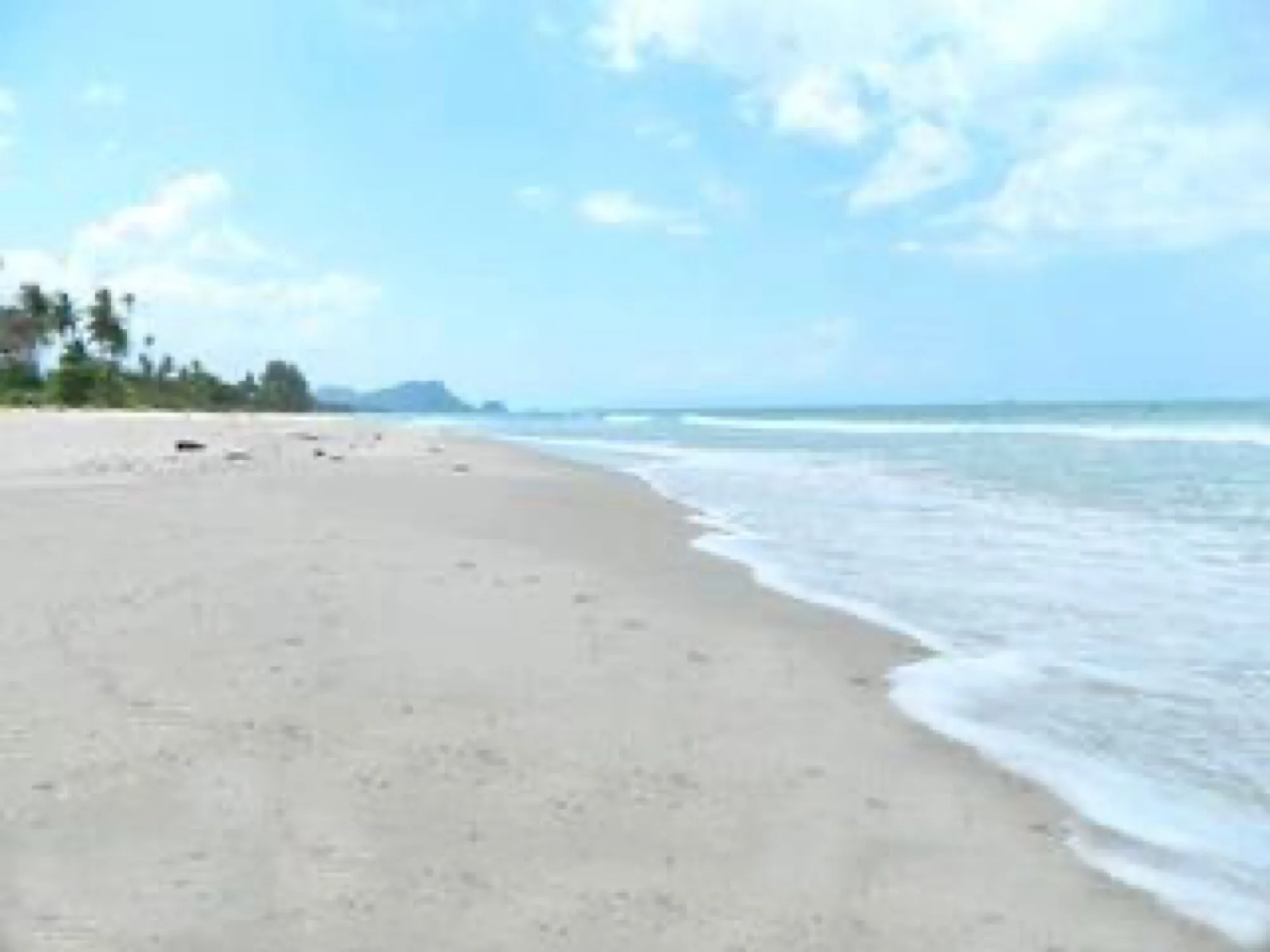 Long flat sand and shallow surf on the bay at Khanom