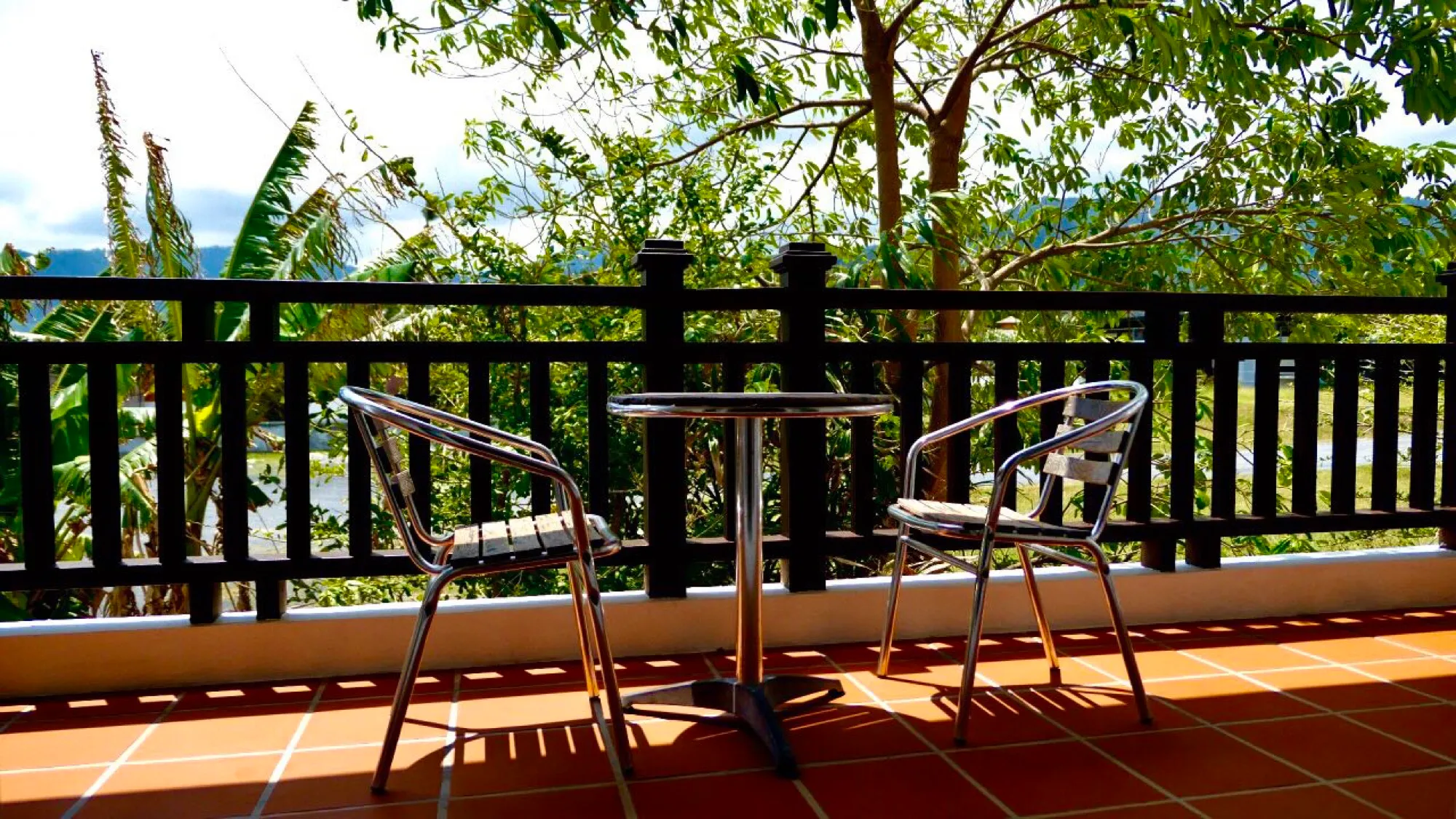 Balcony table and chairs, trees and the water beyond